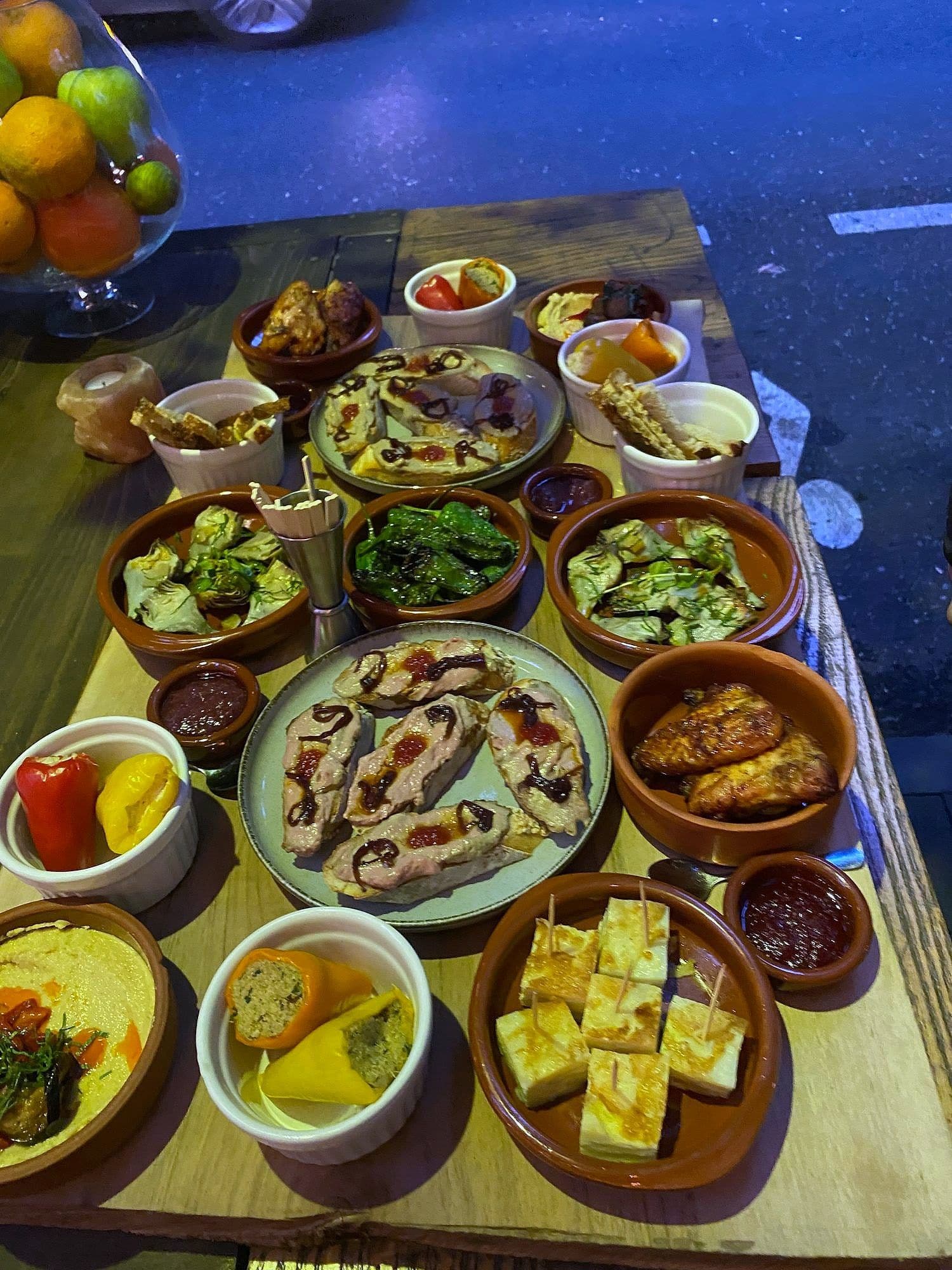 Long table set with terracotta dishes of dips, cured fish, grilled vegetables, cheese and pickles