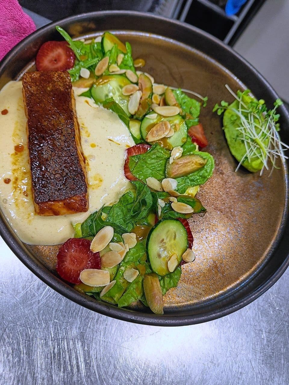 Dark-seared salmon fillet on pale purée with cucumber, strawberry, toasted almond and leaves