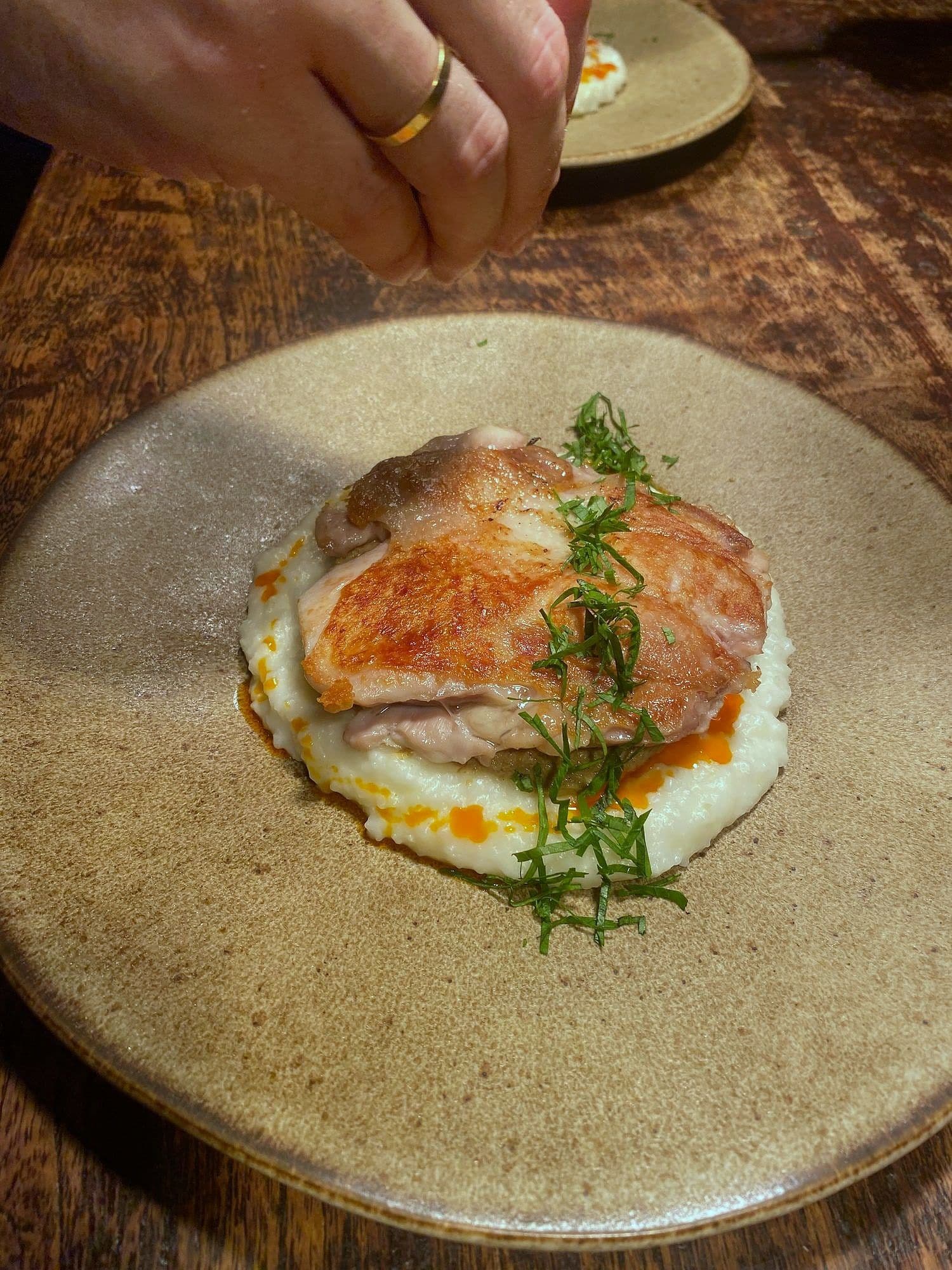 Crisp-skinned chicken thigh on pale celeriac purée finished with chilli butter and shredded herbs