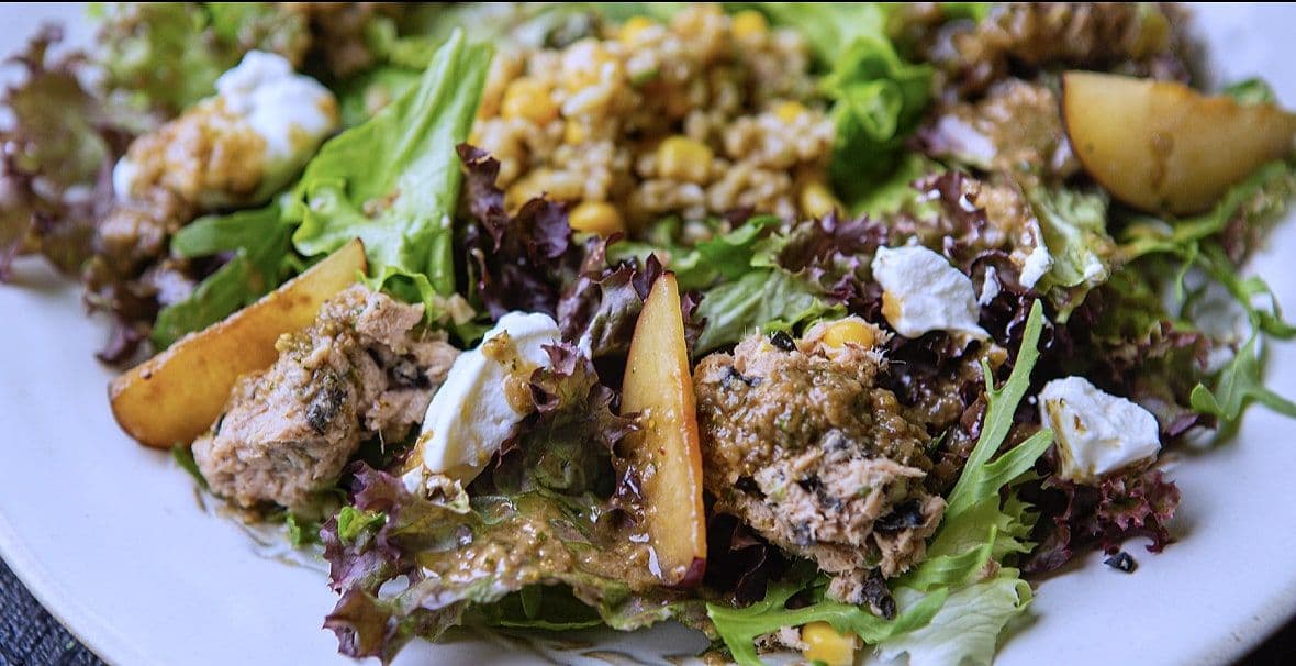 Salad of roast pear, goat cheese, walnuts and mixed leaves on a white plate