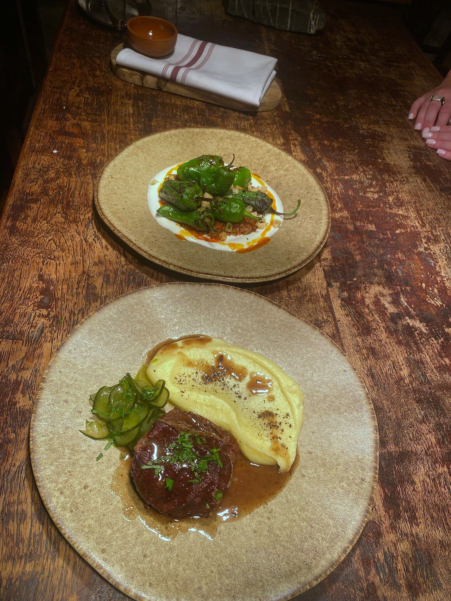 Braised beef in a dark glaze on whipped potato with herbs, on a stoneware plate