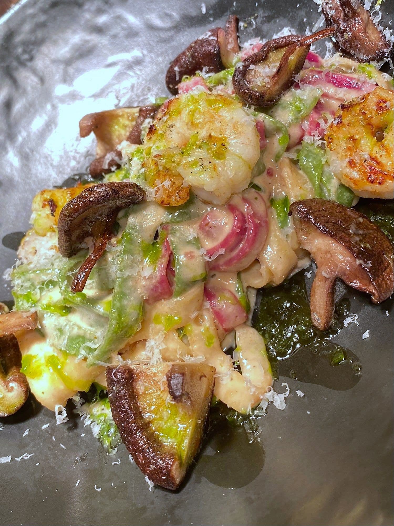 Prawns and mushrooms under melted cheese with green herb oil, on a metal service tray
