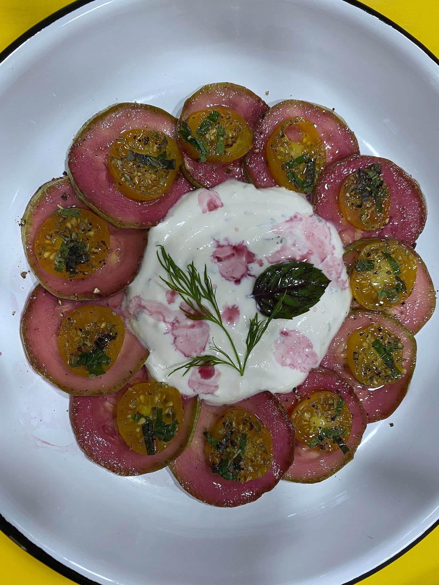 Ring of beetroot and yellow tomato discs around whipped cheese, dressed with herb oil and topped with basil