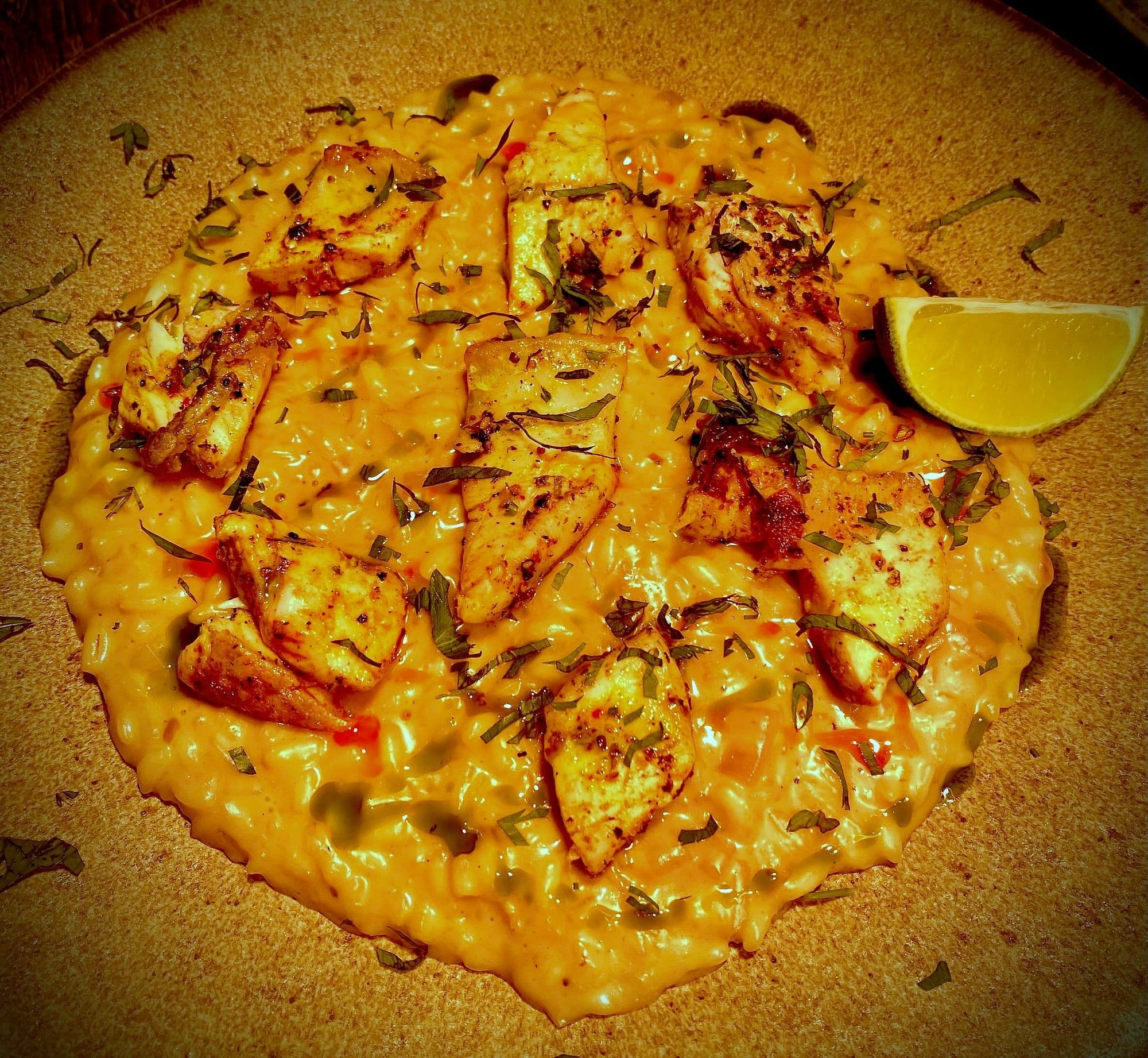 Round cheese-covered flatbread blistered from the oven, with a lemon wedge on the side