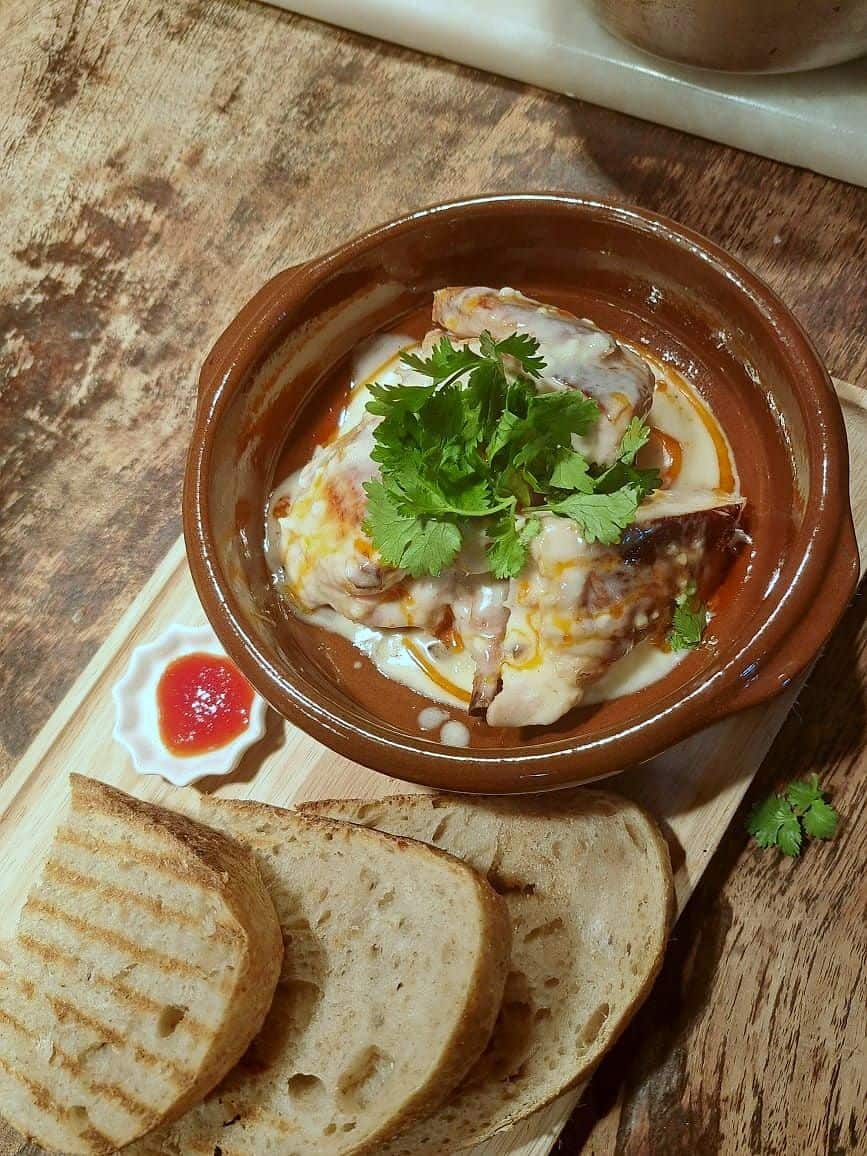 Cheese and egg baked in a terracotta dish topped with fresh coriander, served with slices of grilled bread