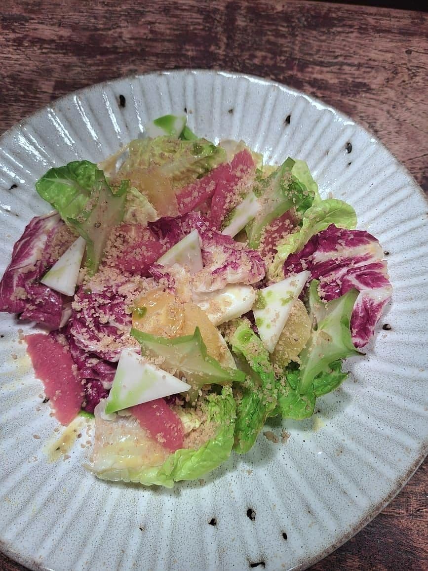 Salad of radicchio, gem lettuce, pear and shaved Parmesan on a fluted white plate