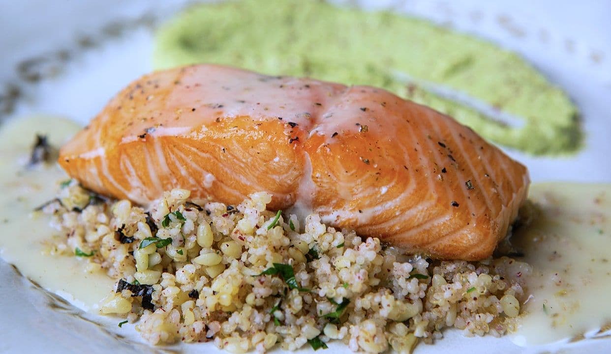 Thick salmon fillet on a herbed grain pilaf with a bright green herb purée