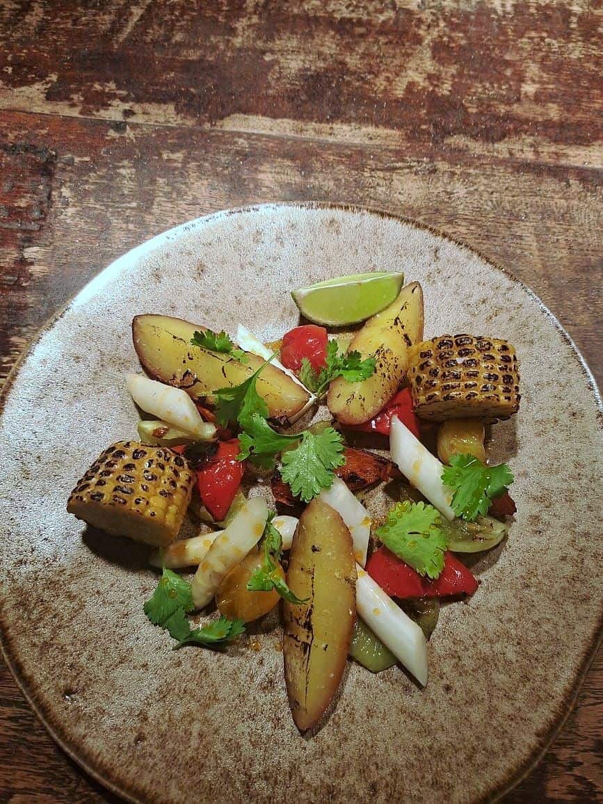Charred corn, ember-roasted potato, white asparagus, red pepper and coriander on a speckled stoneware plate