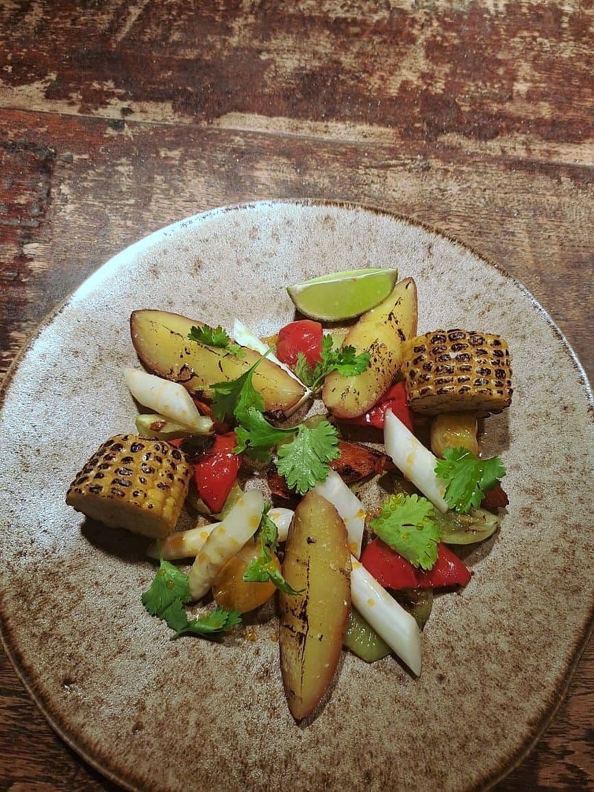 Charred corn, ember-roasted potato, white asparagus, red pepper and coriander on a speckled stoneware plate