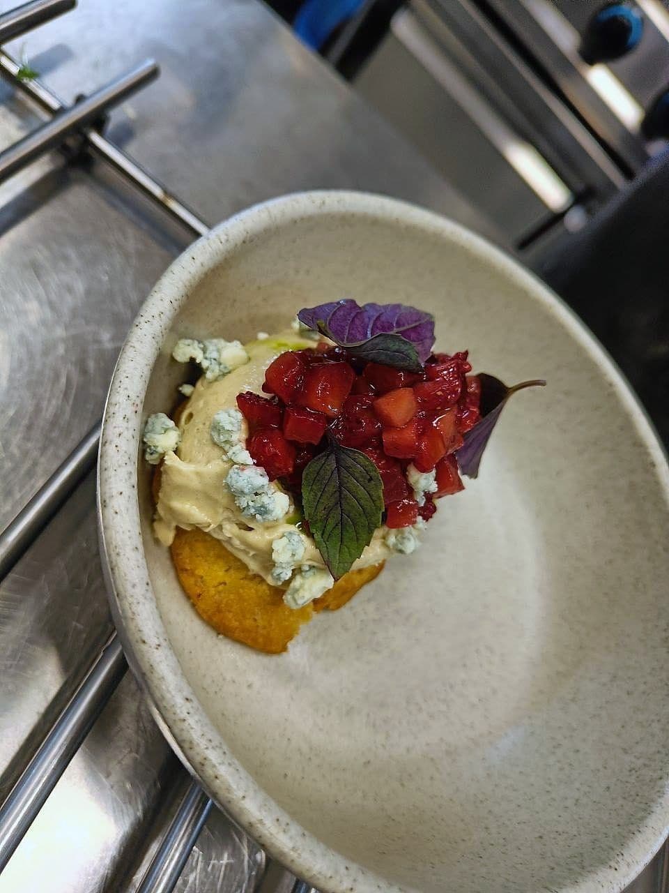 Whipped cheese with crumbled blue cheese and diced strawberry on a fried polenta base, with purple basil